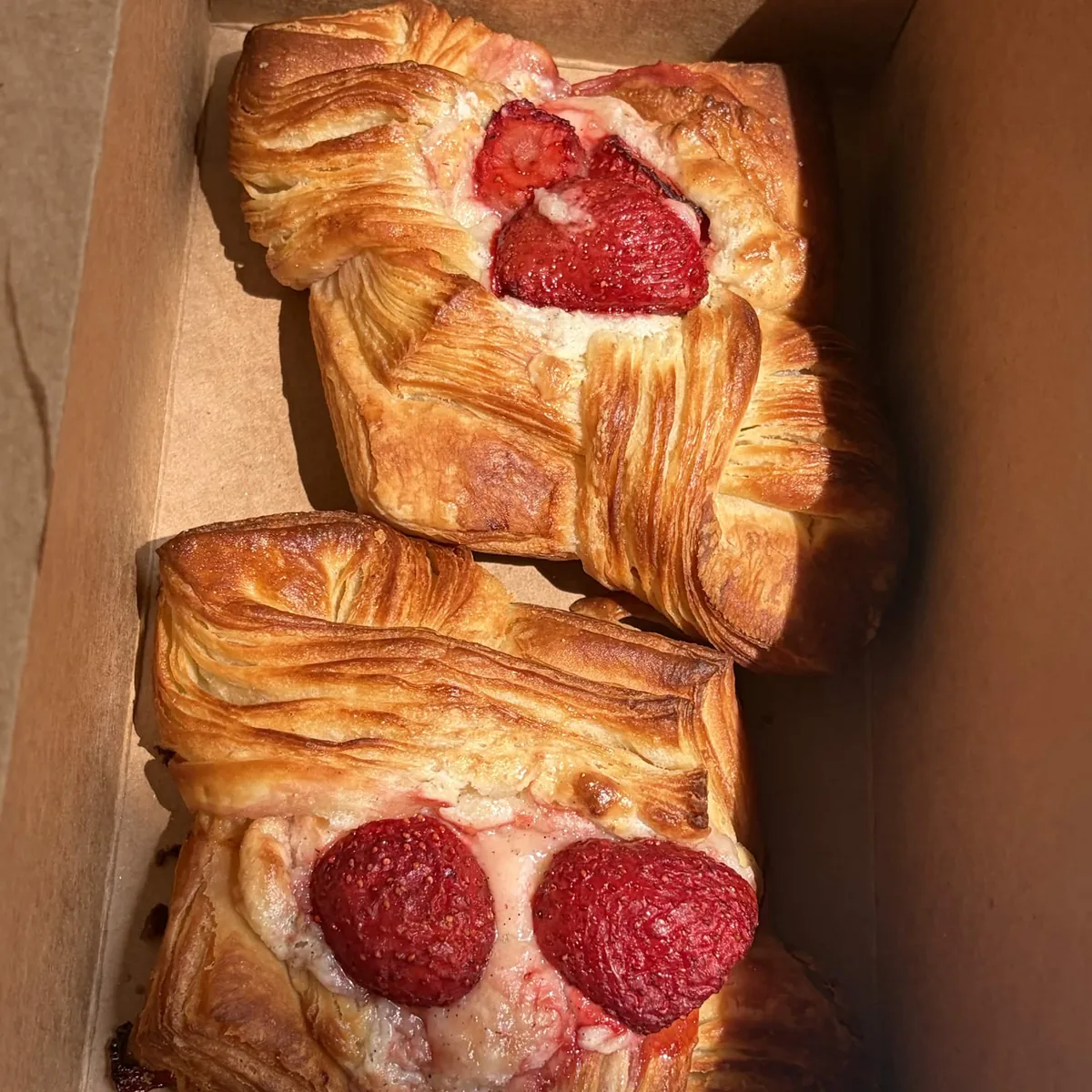 A box of fresh strawberry danishes ready for pickup